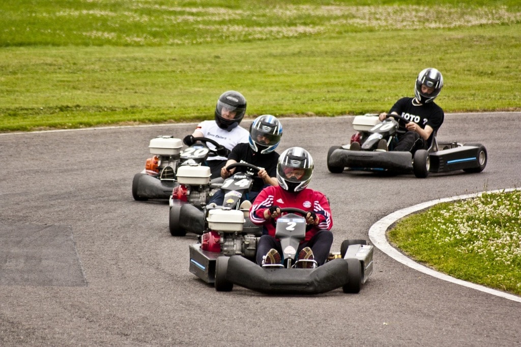 Four men driving go kart on race track
