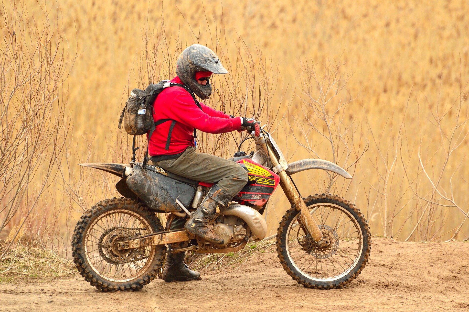 Man is riding his dirt bike with backpack and helmet