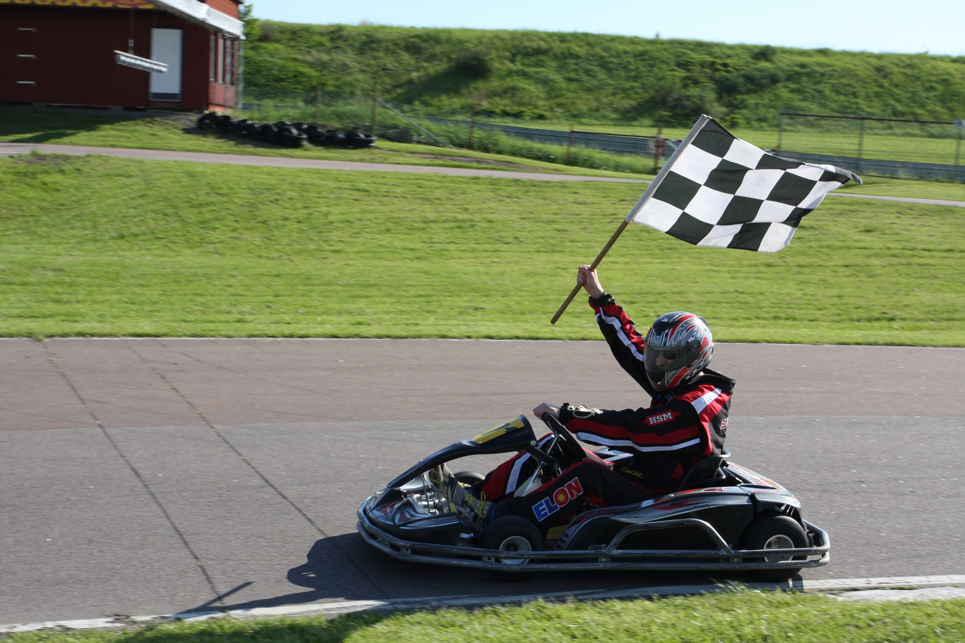 Man holding a race flag is driving the go kart vehicle